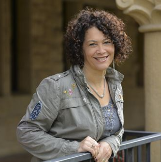 A smiling woman leaning against railing